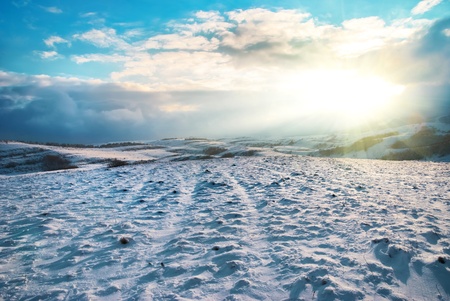 Winter hills covered by snow against sunsetの写真素材