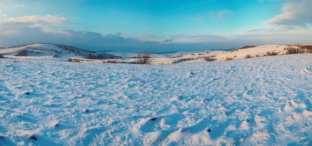 Panorama with winter hills covered by snow against sunsetの写真素材
