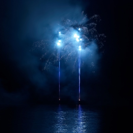 Blue colorful fireworks on the black sky background. Holiday celebration.の写真素材