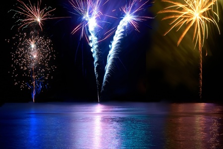 Blue, red, white and yellow colorful fireworks above the river. Holiday celebration.