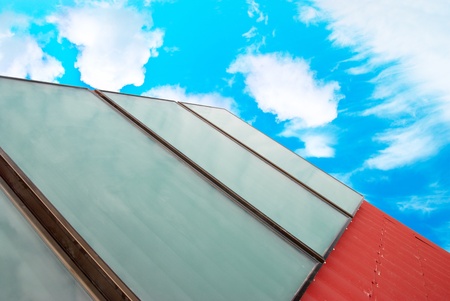 Solar system on the red house roof with blue sunny sky and clouds.の写真素材