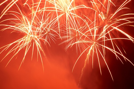 Red colorful fireworks on the black sky background. Holiday celebration.の写真素材
