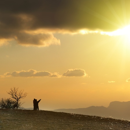 Couple on the hill against sunset. Landscape with clouds and sky.の写真素材