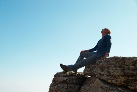 Man gesturing on the rock with blue backgroundの写真素材