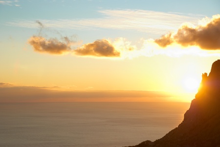 Sunset above the sea with red sky, sun, clouds and mountainの写真素材