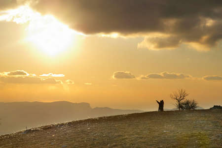 Couple on the hill against sunset. Landscape with clouds and sky.の写真素材