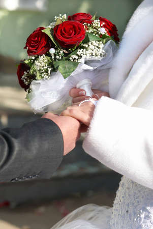 A bride and a groom with bouquet holding hands on the wedding day. の写真素材