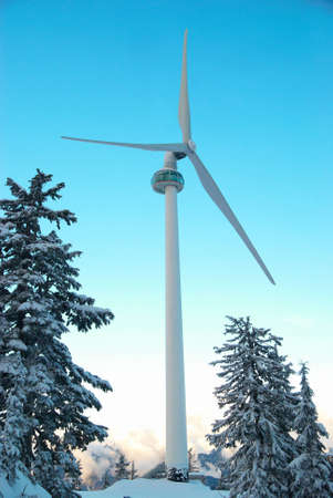 Wind turbine in the mountain covered with winter forestの写真素材