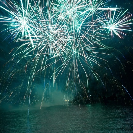 Green colorful fireworks on the black sky background. Holiday celebration.の写真素材