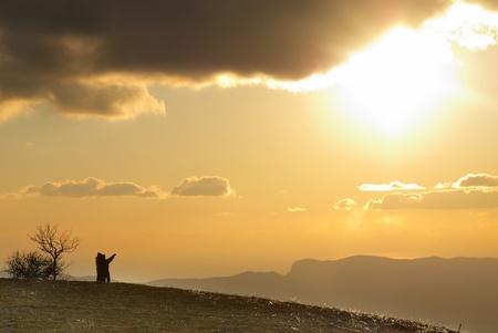Couple on the hill against sunset. Landscape with clouds and sky.の写真素材
