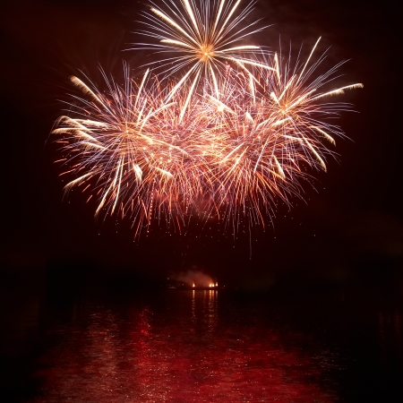 Red colorful holiday fireworks on the black sky background の写真素材