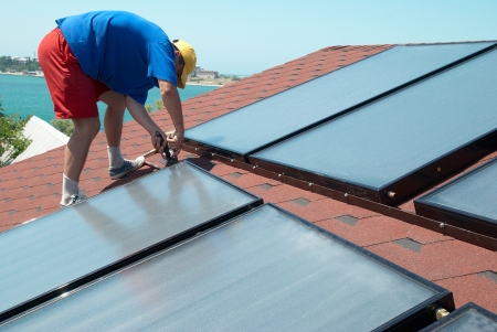 Worker solar water heating panels on the roof.の写真素材