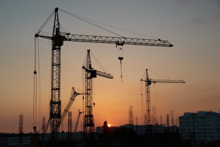 Industrial landscape with silhouettes of cranes on the sunset backgroundの写真素材