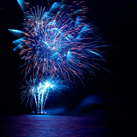 Blue and red colorful holiday fireworks on the black sky background.の写真素材
