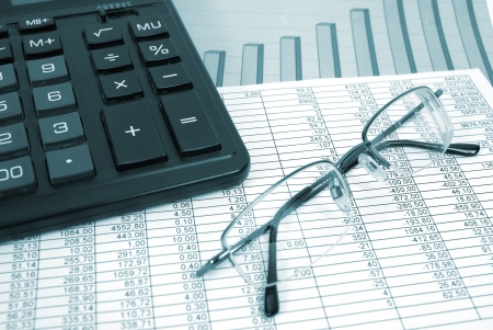 Glasses and calculator on paper table with finance diagramの写真素材