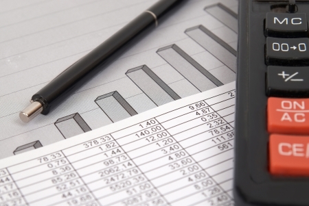 Pen and calculator on paper table with finance diagramの写真素材