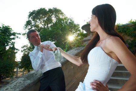 Beautiful wedding couple. Bride pulling groom by the tieの写真素材