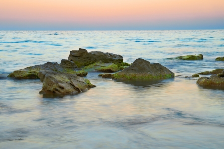 Rocks in the sea against beautiful sunsetの写真素材