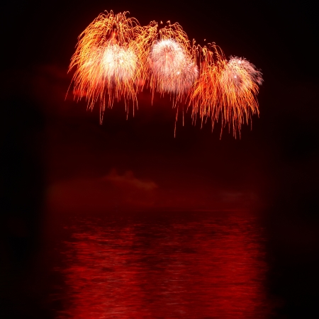 Red colorful holiday fireworks on the black sky background.の写真素材