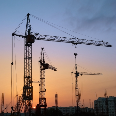 Industrial landscape with silhouettes of cranes on the sunset backgroundの写真素材