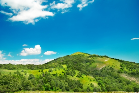 Green mountain covered with forest on the blue sky backgroundの写真素材