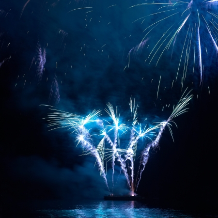 Blue colorful holiday fireworks on the black sky background の写真素材