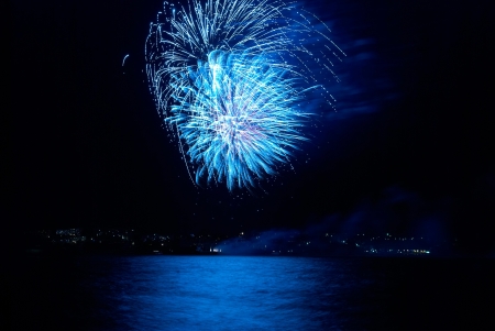 Blue colorful holiday fireworks on the black sky background の写真素材