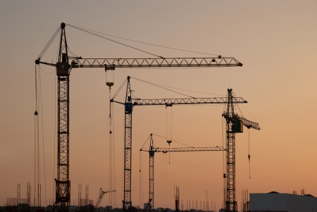 Industrial landscape with silhouettes of cranes on the sunset backgroundの写真素材