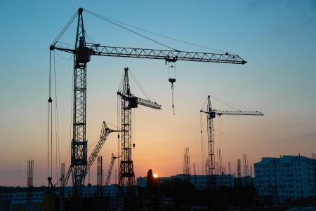 Industrial landscape with silhouettes of cranes on the sunset backgroundの写真素材