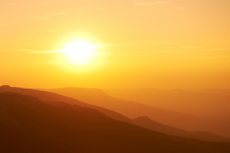 Beautiful sunset at the mountains. Colorful landscape with sun and orange skyの写真素材