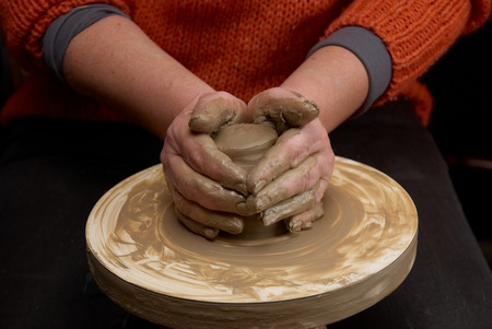 Female hands forming clay pot on the pottery wheel の写真素材