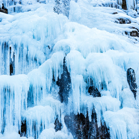 Frozen waterfall of blue icicles on the rockの写真素材