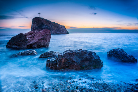 Sunset on the beach with sea, rocks and dramatic skyの写真素材