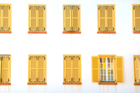 Many closed windows with shutters on the white wallの写真素材