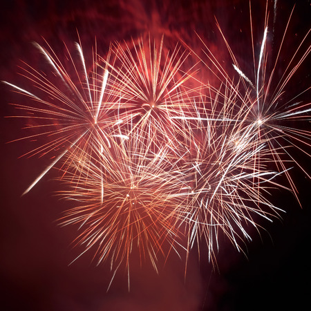 Red colorful fireworks on the black sky background. Holiday celebration.の写真素材