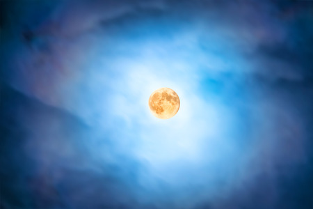 Night view at the full moon through moving blue clouds. Abstract sceneの写真素材