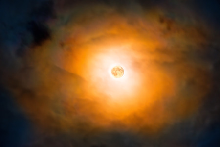 Night view at the full moon through moving orange clouds. Abstract scene