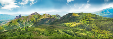 Green mountains covered with forest on the blue sky background. Panoramaの写真素材