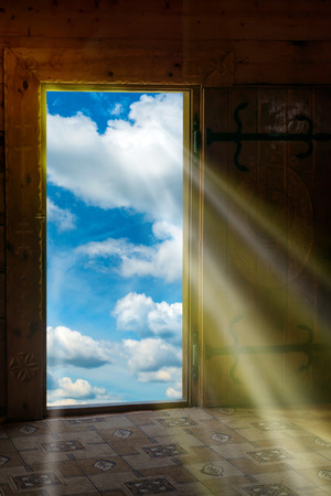 Sun light shining through wooden door from new world with blue sky and cloudsの写真素材