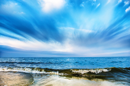 Tropical beach and blue sea with waves, white clouds on backgroundの写真素材
