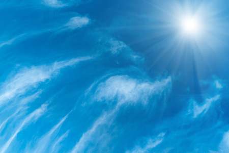 Beautiful blue sky, fluffy white clouds and shining sun with raysの写真素材