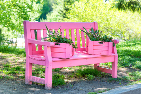 Pink bench with flowers in the green spring parkの写真素材