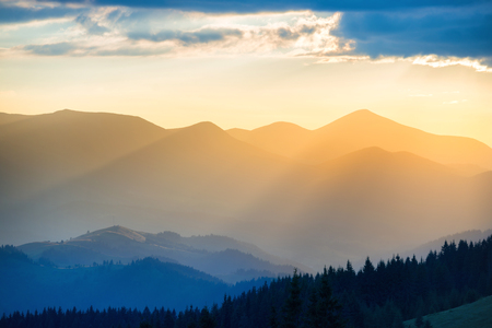 Beautiful sunset in the mountains. Landscape with sun shining through orange cloudsの写真素材