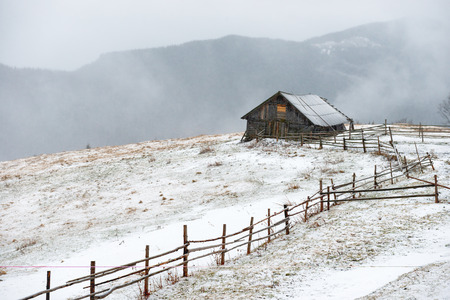 Small rural house in the white winter mountainsの写真素材