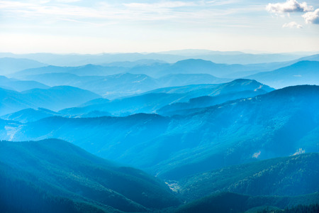 Landscape with blue mountains, forest and white clouds on skyの写真素材