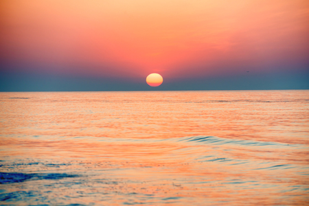 Sunset or sunrise over sea with sun on beautiful dramatic skyの写真素材