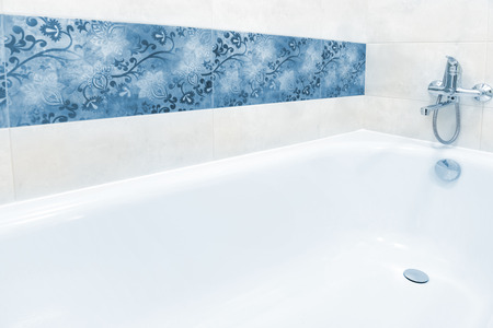 Close up of white and blue bathtub in bathroom interior