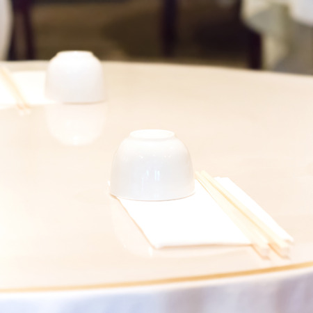 Table setting in Chinese restaurant. Tea cup and chopsticks in napkinの写真素材