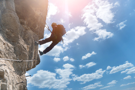 Silhouette of via ferrata climber climbing on rockの写真素材