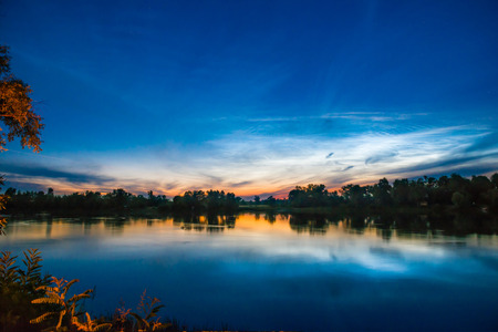 Sunset on a lake with forest with reflection in waterの写真素材